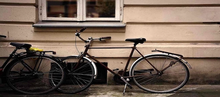 Bicycles parked against a beige building beneath a window