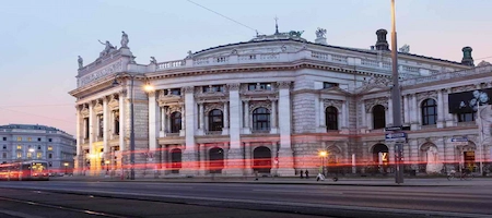 Burgtheater in Vienna at dusk with red light trails across the foreground