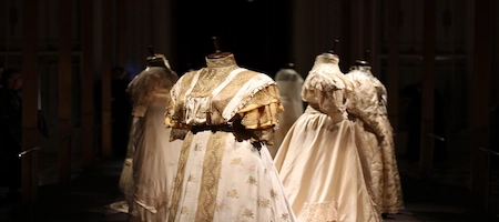 Historic dresses with lace and full skirts displayed on mannequins