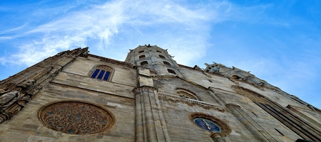 Upward view of St. Stephen’s Cathedral’s stone façade and rose window against a blue sky
