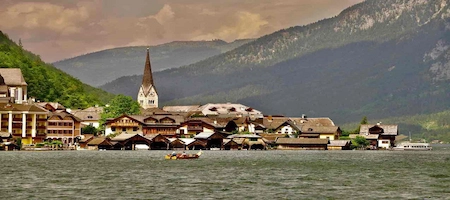 Hallstatt village with lakeside houses, a church spire and mountains in the background
