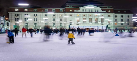People skating on an outdoor ice rink in Vienna at night