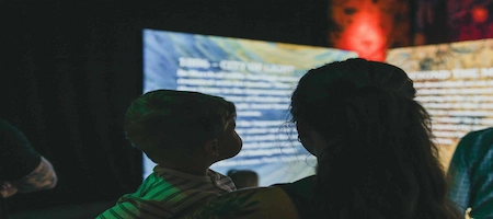 Adult and child in front of an illuminated museum display