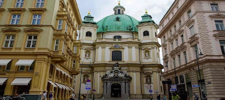Peterskirche’s Baroque façade and green dome between historic buildings in Vienna