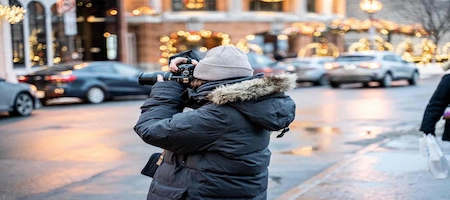 Photographer in winter clothing taking pictures on a city street