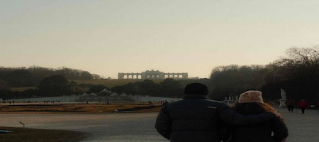 Couple embracing in Schönbrunn Palace gardens with the Gloriette in the background