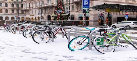 Bicycles parked at racks on a snowy Vienna street