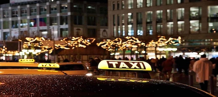 Illuminated taxi roof signs with festive city lights in the background