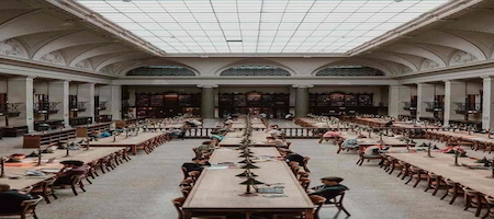University of Vienna library reading room with study tables beneath a large skylight