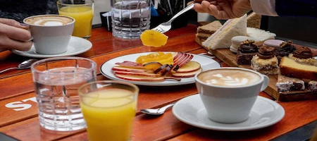 Coffee, assorted cakes, sliced apples and fruit juice on a café table