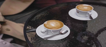 Two cups of Viennese Melange coffee with milk foam on a marble table