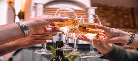 People toasting with glasses of white wine around a table