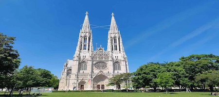 Votivkirche in Vienna with twin Gothic spires overlooking a green lawn